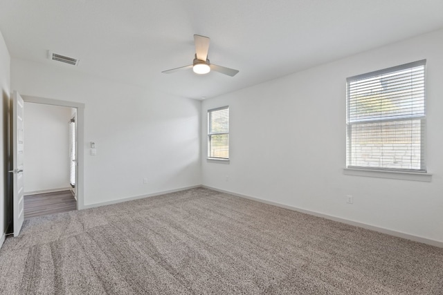 carpeted empty room with ceiling fan and plenty of natural light