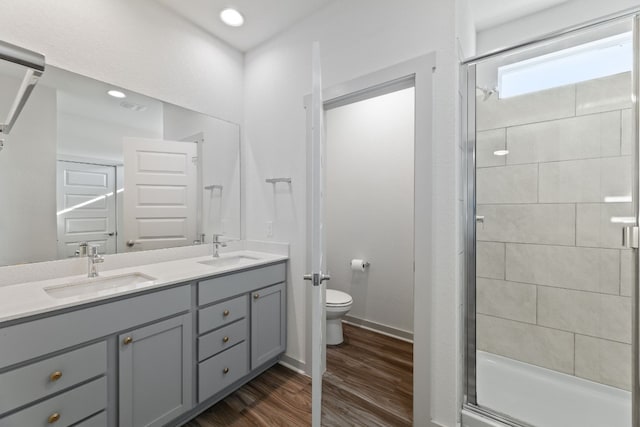 bathroom featuring hardwood / wood-style floors, toilet, vanity, and a shower with shower door