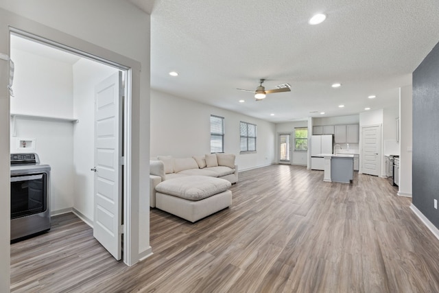 living room featuring sink, wood-type flooring, ceiling fan, a textured ceiling, and washer / clothes dryer