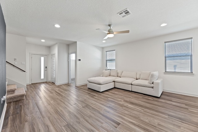 unfurnished living room with ceiling fan, a textured ceiling, a wealth of natural light, and wood-type flooring