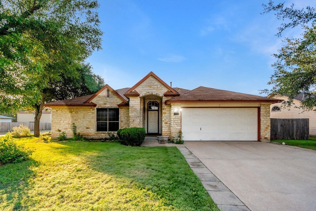 view of front of home featuring driveway, a garage, fence, and a front yard