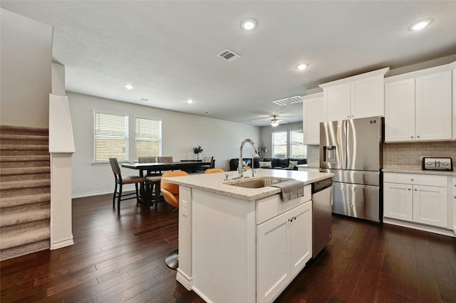 kitchen featuring stainless steel appliances, sink, a center island with sink, ceiling fan, and dark wood-type flooring