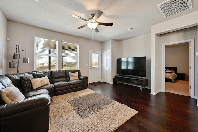 living room featuring a textured ceiling, ceiling fan, and dark wood-type flooring