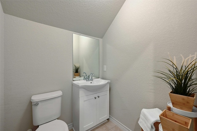 bathroom with toilet, vanity, tile patterned floors, a textured ceiling, and lofted ceiling