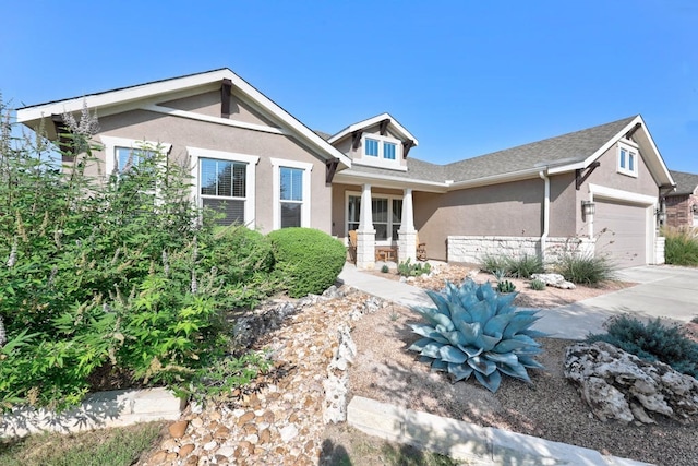 craftsman house featuring a garage, concrete driveway, stone siding, and stucco siding