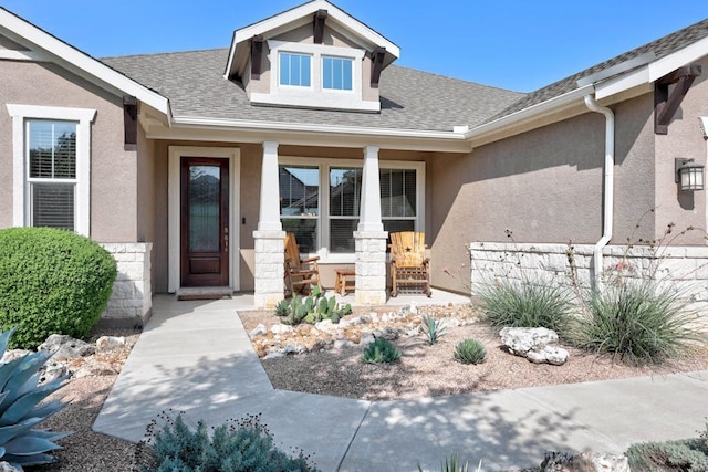 view of exterior entry featuring stone siding, a shingled roof, and stucco siding