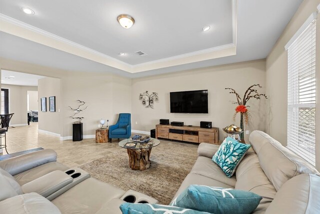 living room with light tile patterned flooring, a raised ceiling, and crown molding