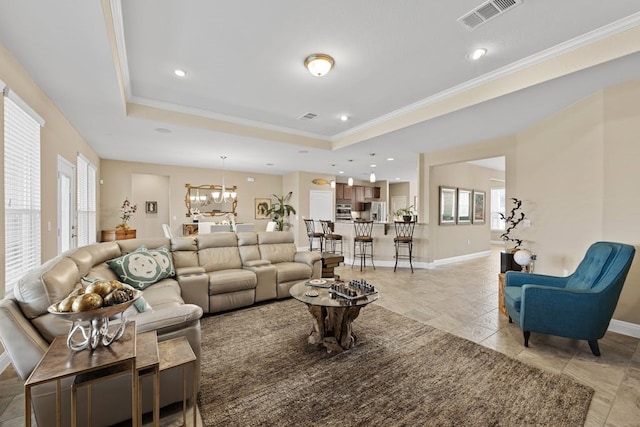 tiled living room with a raised ceiling, a healthy amount of sunlight, a chandelier, and ornamental molding