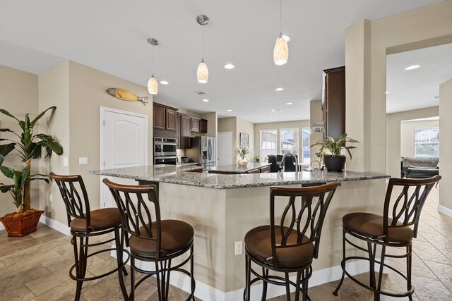 kitchen with light tile patterned floors, a kitchen bar, dark brown cabinetry, and plenty of natural light