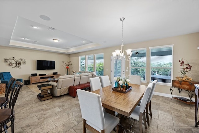 dining area with light tile patterned floors, a raised ceiling, and a chandelier