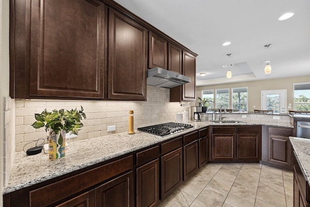 kitchen featuring decorative backsplash, ventilation hood, stainless steel gas stovetop, light stone counters, and light tile patterned flooring