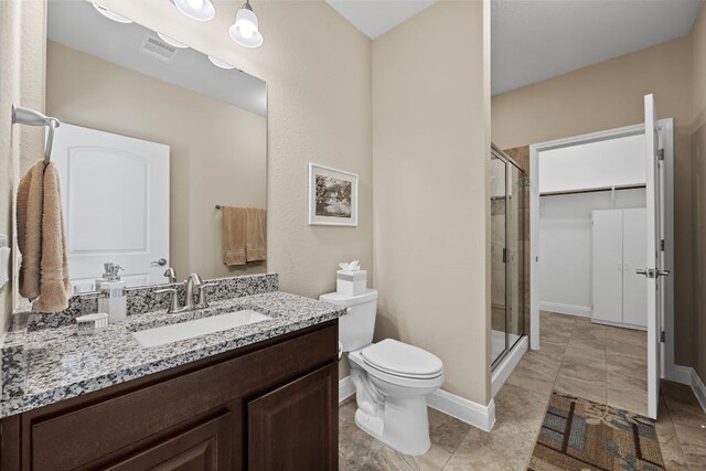 bathroom featuring toilet, vanity, walk in shower, and tile patterned floors