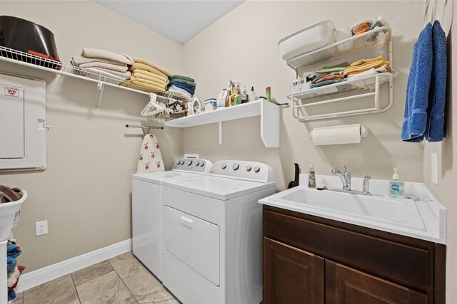 laundry area featuring sink, washing machine and dryer, cabinets, and light tile patterned floors