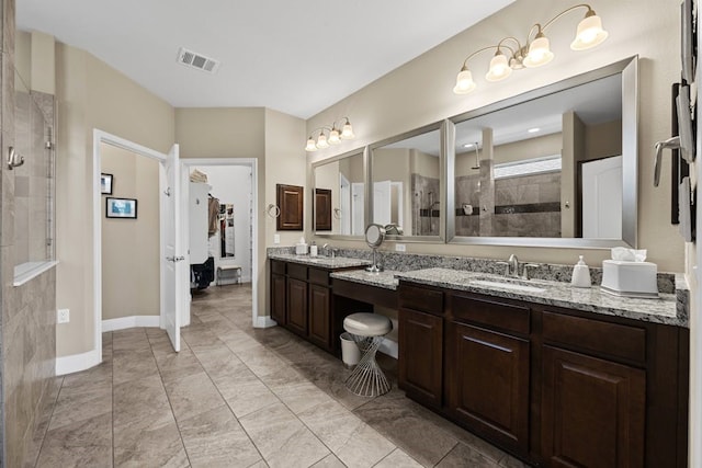 bathroom with tile patterned flooring, a tile shower, and vanity