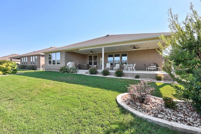 back of property featuring ceiling fan, a lawn, fence, and stucco siding