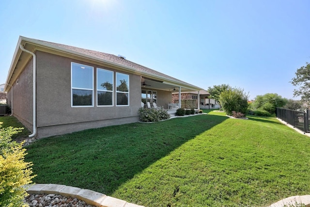 back of house featuring stucco siding, fence, and a yard