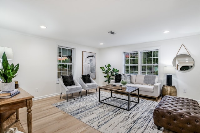 living room with crown molding, plenty of natural light, and light hardwood / wood-style flooring