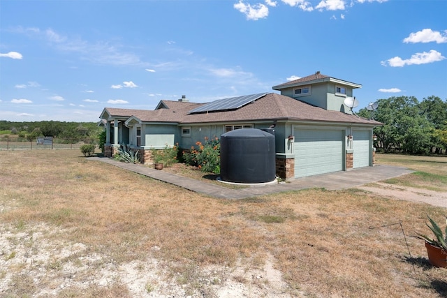 view of side of property with a lawn, a garage, and solar panels