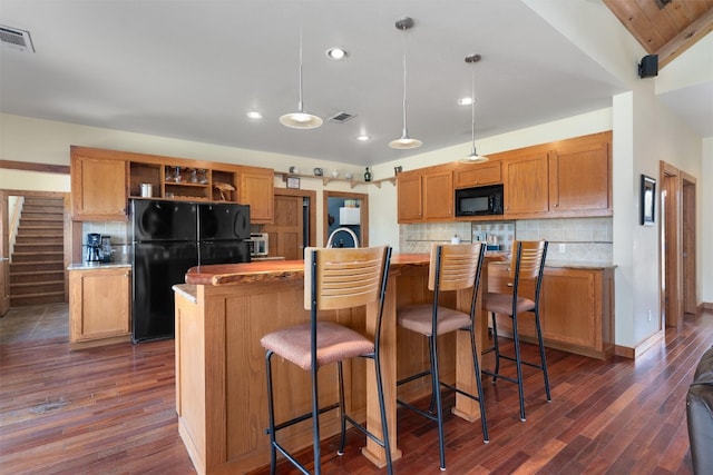 kitchen with pendant lighting, black appliances, a center island with sink, and dark hardwood / wood-style flooring