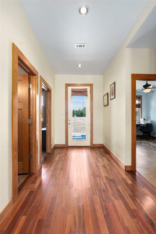 corridor with dark wood-style floors, baseboards, and visible vents