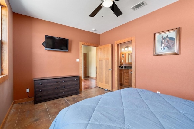 bedroom with ceiling fan, connected bathroom, dark tile patterned floors, visible vents, and baseboards