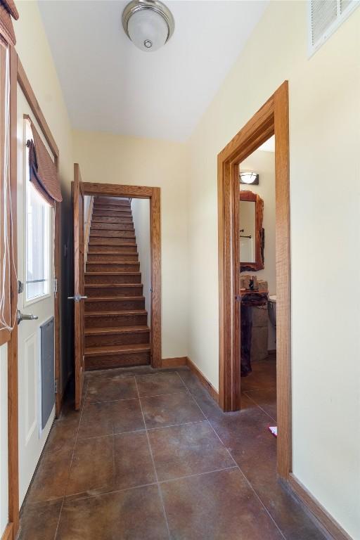 hall with baseboards, stairs, visible vents, and dark tile patterned flooring