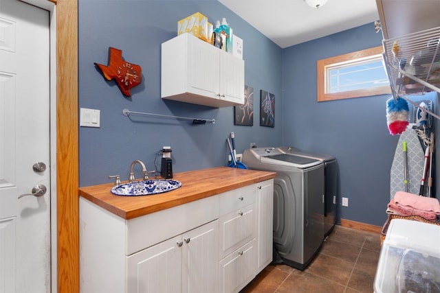 laundry area with washing machine and clothes dryer, dark tile patterned floors, cabinets, and sink