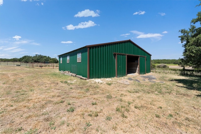 view of pole building with a yard, a rural view, and fence