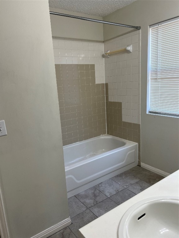 bathroom featuring a wealth of natural light, tiled shower / bath, a textured ceiling, and tile patterned flooring