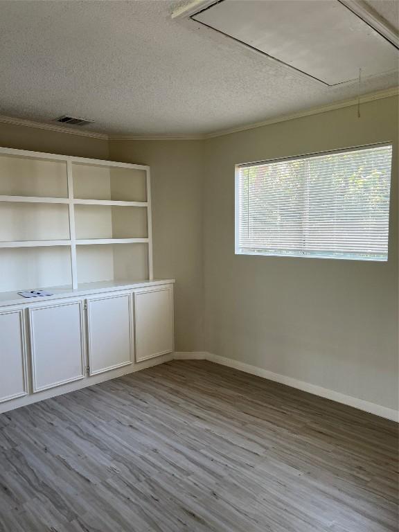 spare room featuring attic access, visible vents, baseboards, a textured ceiling, and light wood-style floors