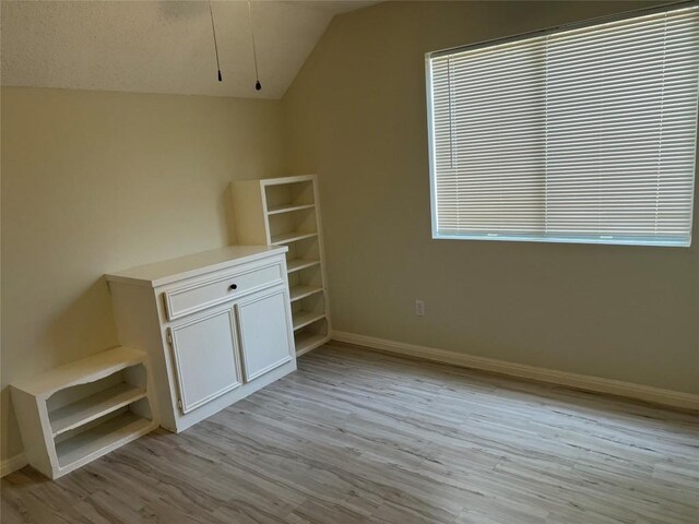 additional living space with a textured ceiling, lofted ceiling, and light wood-type flooring