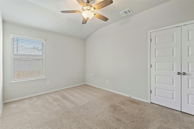 spare room with ceiling fan, vaulted ceiling, and light carpet