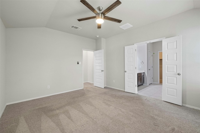 unfurnished bedroom featuring ceiling fan, ensuite bath, lofted ceiling, and light colored carpet