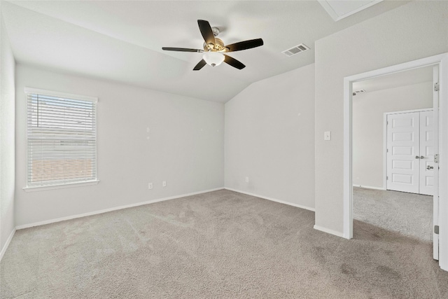 empty room featuring ceiling fan, vaulted ceiling, and light carpet