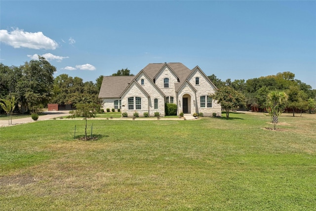 french provincial home with stone siding and a front lawn