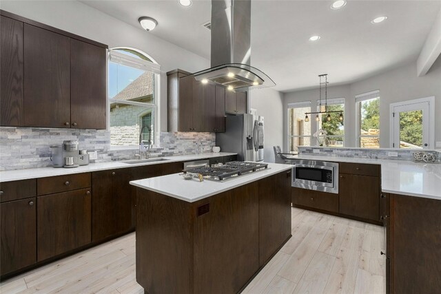 kitchen with sink, light hardwood / wood-style floors, island range hood, a kitchen island, and appliances with stainless steel finishes