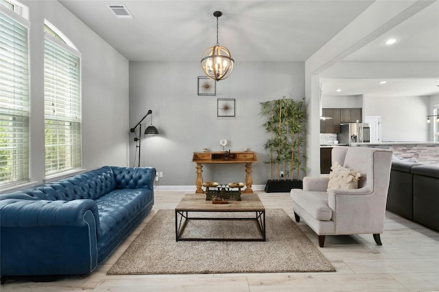 living room with a wealth of natural light, light hardwood / wood-style flooring, and a notable chandelier