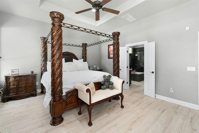 bedroom with a raised ceiling, ceiling fan, and light wood-type flooring