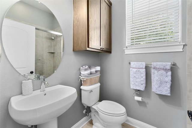 bathroom featuring toilet, a shower with door, and sink