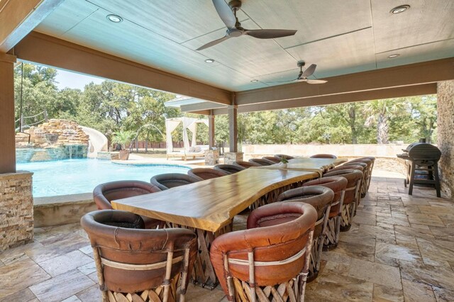 view of patio / terrace with ceiling fan, an outdoor bar, grilling area, pool water feature, and a fenced in pool