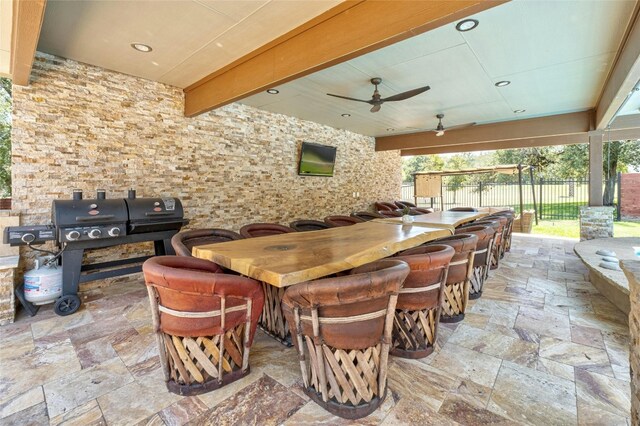 view of patio with area for grilling, ceiling fan, and a bar