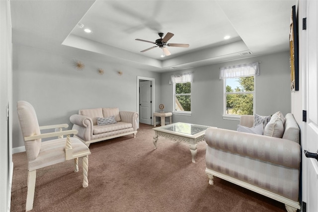 carpeted living room featuring ceiling fan and a raised ceiling