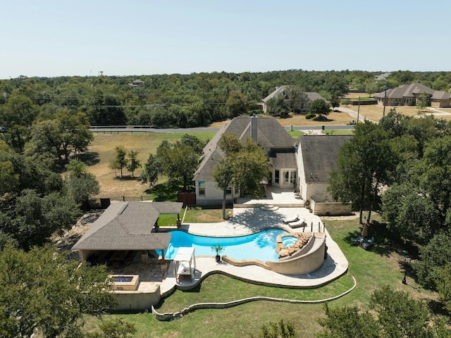 view of swimming pool featuring a forest view, a patio area, a fenced backyard, and a pool with connected hot tub