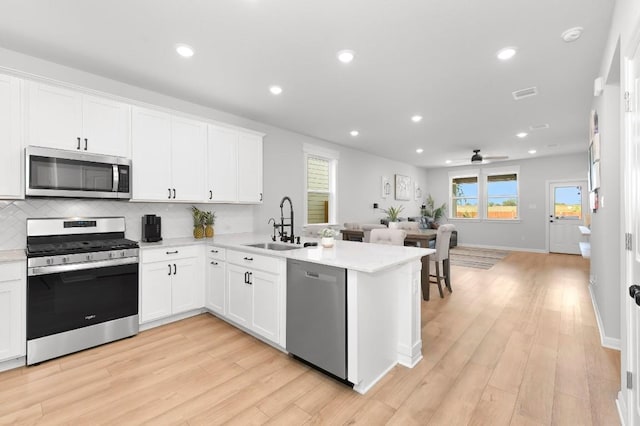 kitchen with light hardwood / wood-style flooring, white cabinets, and stainless steel appliances