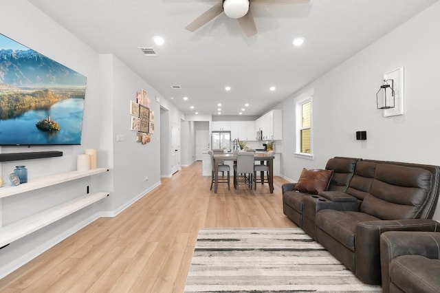 living room featuring ceiling fan and light hardwood / wood-style floors