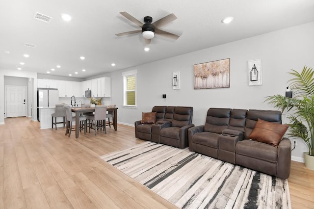 living area with ceiling fan, recessed lighting, light wood-type flooring, and baseboards