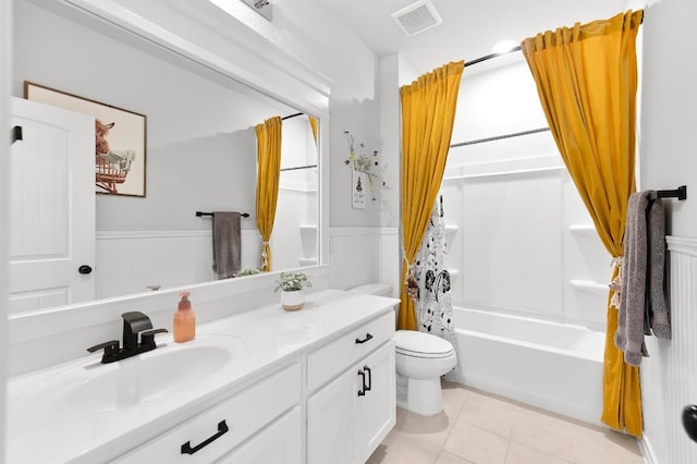 full bath with wainscoting, toilet, vanity, tile patterned floors, and shower / bath combo