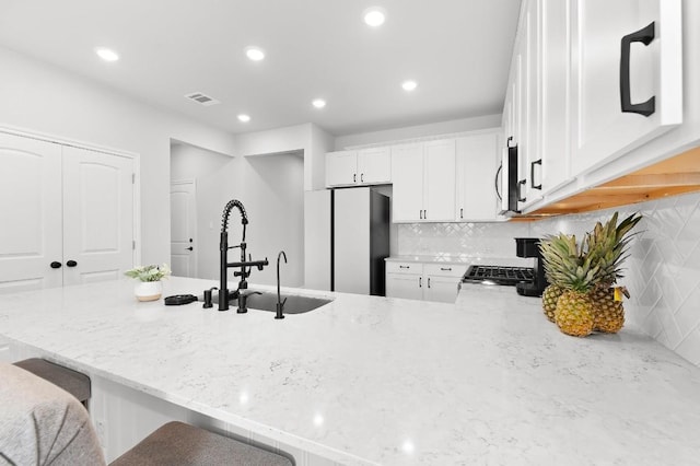 kitchen featuring backsplash, white cabinets, a kitchen breakfast bar, and white refrigerator