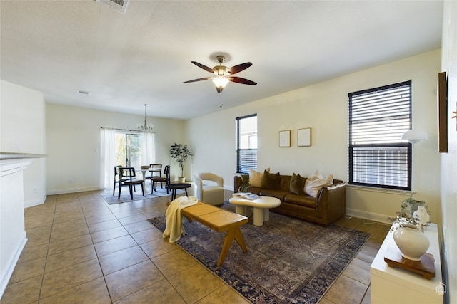 tiled living room featuring ceiling fan with notable chandelier