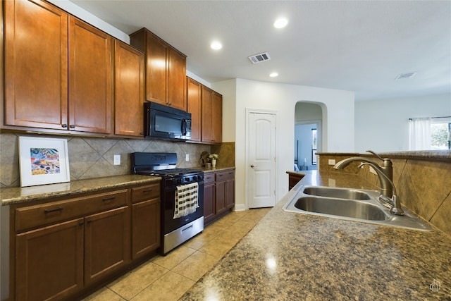 kitchen featuring decorative backsplash, light tile patterned flooring, stainless steel range with gas cooktop, and sink